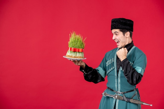 Бесплатное фото Портрет азербайджанца в традиционном костюме, держащего студию семени, выстрелил в красный цвет