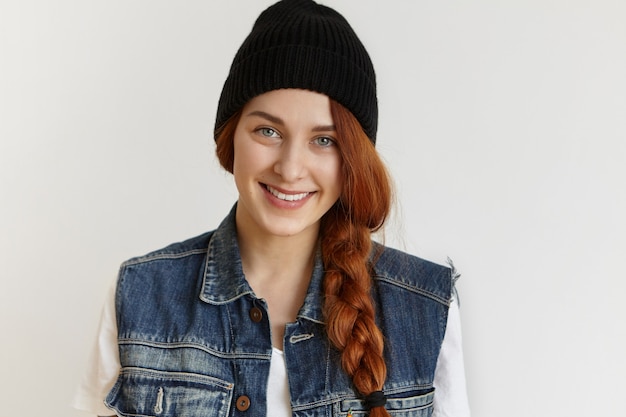 無料写真 スタイリッシュな黒の冬の帽子とノースリーブのデニムジャケットを着て美しい陽気な赤毛の女の子の肖像画