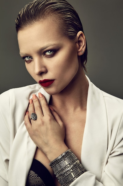 Бесплатное фото Портрет красивой модной стильной модели брюнетки с вечерним макияжем и красными губами в белой куртке