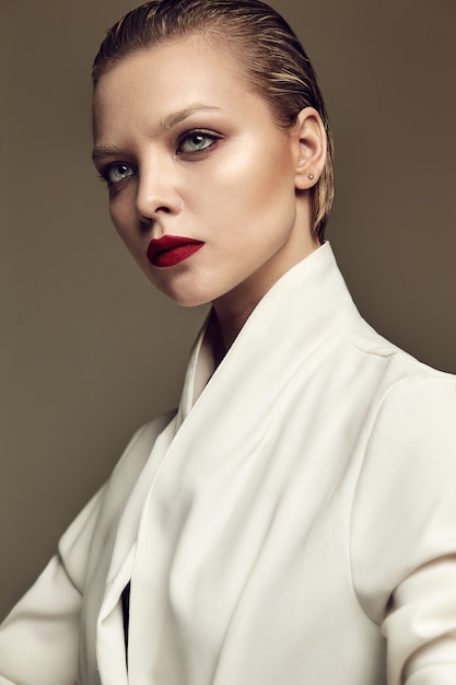 Бесплатное фото Портрет красивой модной стильной модели брюнетки с вечерним макияжем и красными губами в белой куртке