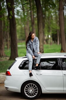 高級白い車の上に座ってリラックスできるジーンズのジャケットで美しいセクシーなファッションブルネットの女性モデルの肖像画 ファッションのコンセプトです 車で女の子の写真撮影のためのアイデア 垂直 プレミアム写真 高級白い車の上に座ってリラックスできるジーンズのジャケットで美しいセクシーなファッションブルネットの女性モデルの肖像画 ファッションのコンセプトです 車で女の子の写真撮影のためのアイデア 垂直 プレミアム写真