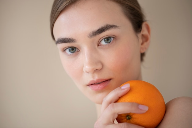 無料写真 オレンジ色の果物を保持している透明な肌を持つ美しい女性の肖像画