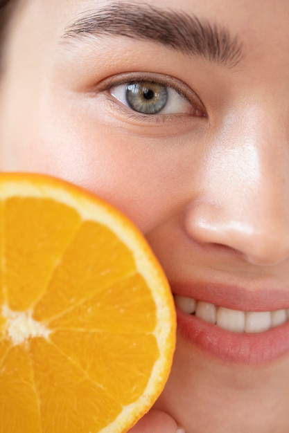 무료 사진 얇게 썬 오렌지 과일을 들고 맑은 피부를 가진 아름다운 여성의 초상화