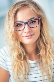 眼鏡​を​かけた​金髪​の​若い​女性​の​肖像画​。