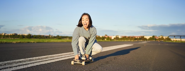 無料写真 心配のない幸せなアジアの女の子の肖像画 スケート スケートボードに乗って 笑って 晴れた日を楽しんで