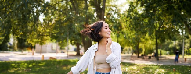 無料写真 心配のない若いアジア人女性の肖像画 公園で一人で踊り 自由を楽しみ 喜びで微笑んでいる