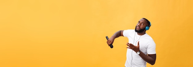 무료 사진 마이크를 잡고 헤드폰을 끼고 있는 밝고 긍정적인 세련된 잘생긴 아프리카 남자의 초상화