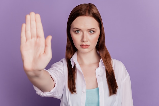 自信​を​持って​怒っている​女性​の​手​の​肖像画​は​、​紫色​の​背景​に​一時​停止​の​標識​を​表示します