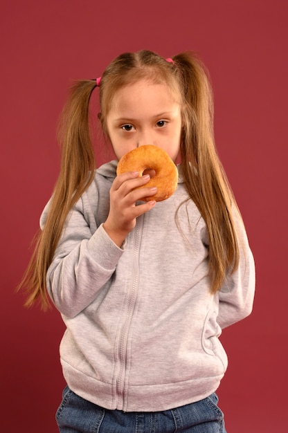 Бесплатное фото Портрет милая молодая девушка ест пончик