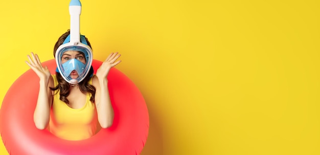 Бесплатное фото Портрет восторженной молодой женщины в отпуске в маске для подводного плавания и плавательном круге