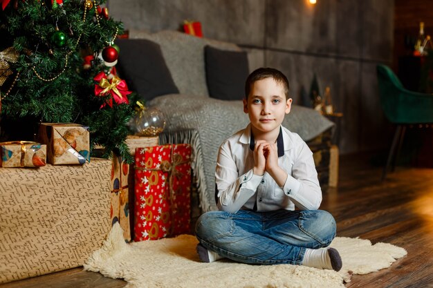 家でクリスマスイブの間にプレゼントを開く興奮した少年の肖像画 プレミアム写真