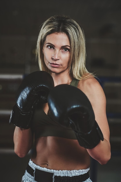 Бесплатное фото Портрет опытной боксерши в боксёрских перчатках и спортивной одежде.