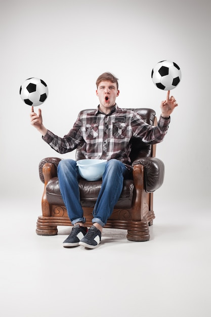 Бесплатное фото Портрет веера с футбольными мячами, держа блюдо на сером
