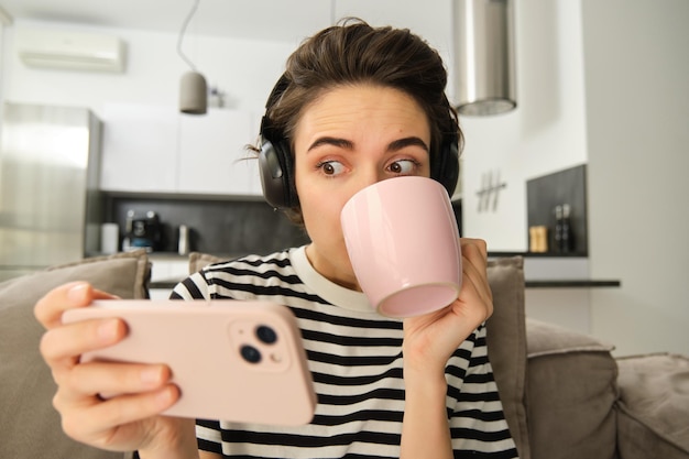 無料写真 お茶を飲み ⁇ スマートフォンでテレビ番組を見ている女の子の肖像画