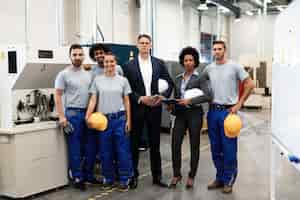 Бесплатное фото Портрет группы инженеров и корпоративных менеджеров, стоящих на заводе и смотрящих в камеру