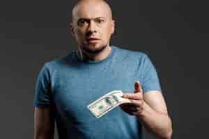Бесплатное фото Портрет красивый мужчина в серой рубашке держит деньги на темной стене