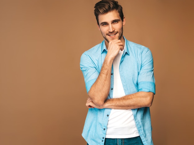 Бесплатное фото Портрет красивый улыбающийся стильный молодой человек модель, одетая в синюю рубашку одежды. модный мужчина позирует