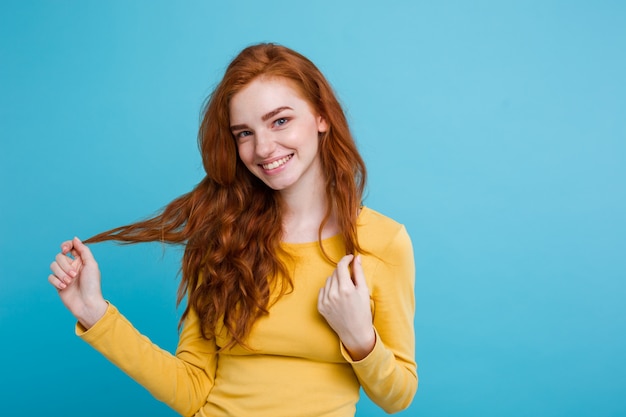 Бесплатное фото Портрет счастливый рыжий рыжий волосы девушка с веснушками, улыбаясь, глядя на камеру. пастель синий фон. копирование пространства.