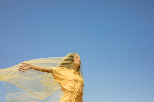 Бесплатное фото Портрет радостной женщины с желтой тканью в природе