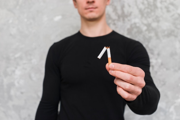 Бесплатное фото Портрет человека, держащего сломанную сигарету