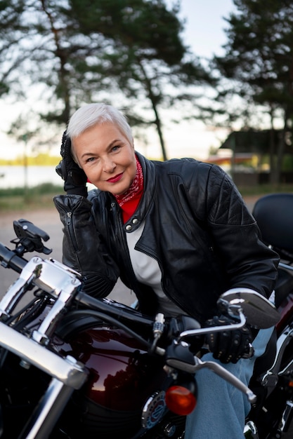 Бесплатное фото Портрет зрелой женщины с мотоциклом на открытом воздухе