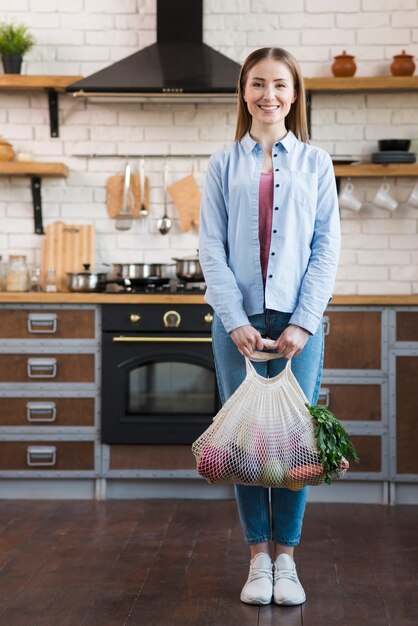 有機野菜を保持している肯定的な若い女性の肖像画