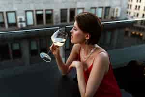 Бесплатное фото Портрет богатой женщины, пьющей вино на открытом воздухе