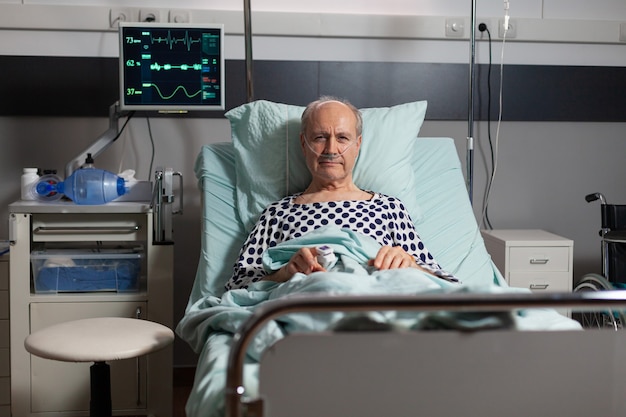 病院​の​ベッド​で​休んでいる​年配​の​男性​患者​の​肖像画
