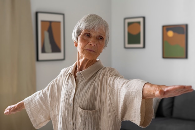 Бесплатное фото Портрет пожилой женщины, растягивающейся дома