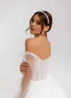 Бесплатное фото Портрет чувственной невесты с модной прической и макияжем, позирующей в белом свадебном платье с украшениями на волосах стильная модная женщина красота лица студийный снимок
