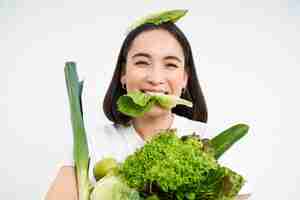 無料写真 笑顔の韓国人女性の肖像画は、栄養価の高い食べ物を食べる緑の野菜を持ったレタスの葉を食べる