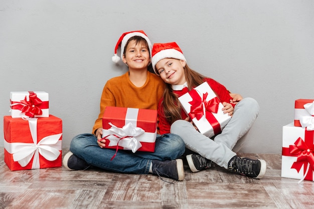 선물 상자와 산타 클로스 모자에 웃는 어린 소년과 소녀의 초상화 프리미엄 사진