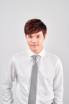 흰색 배경에 고립 된 서 웃는 젊은 아시아 비즈니스 남자의 초상화.