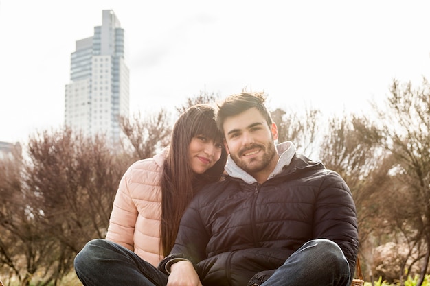 Портрет улыбающейся молодой пары, сидя в парке