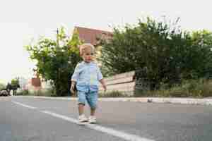 Бесплатное фото Портрет милый маленький мальчик, ходить по дороге в его районе