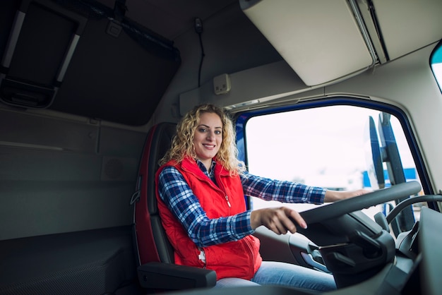 Бесплатное фото Портрет дальнобойщика, сидящего в кабине грузовика с руками на рулевом колесе