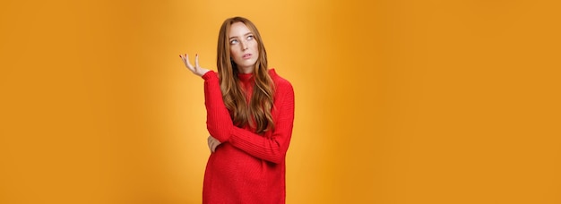 Бесплатное фото Портрет неуверенно думающей рыжей девушки в красном свитере, неуверенно смотрящей в верхний левый угол