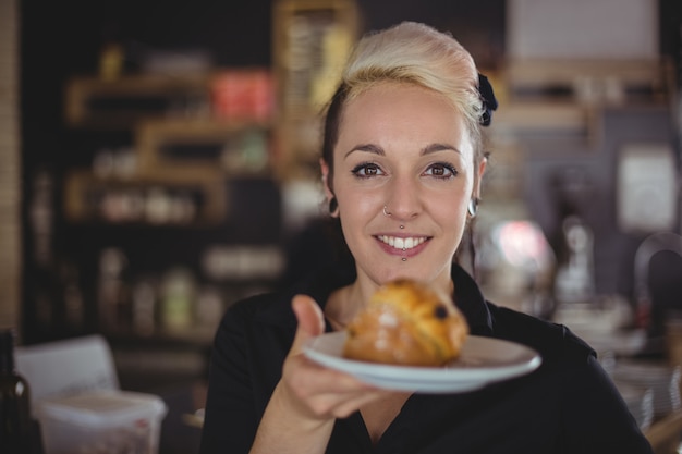 Портрет официантки, держащей тарелку с булочкой