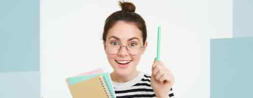 無料写真 メガネをかぶった女性の肖像画 先生がペンで手を上げる ユーレカジェスチャー アイデアやソリューションを持っています