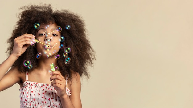 Бесплатное фото Портрет молодой очаровательной девушки позирует, играя с мыльными пузырями