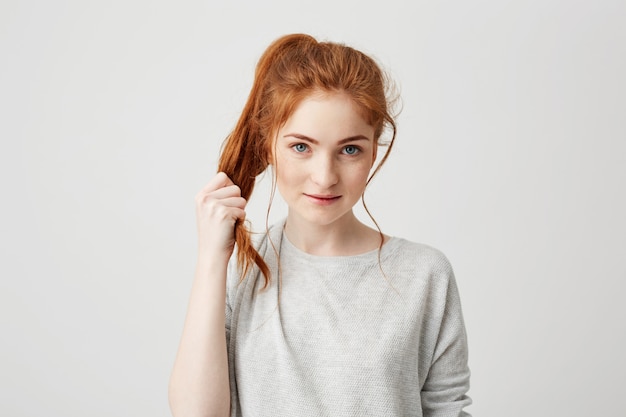 Бесплатное фото Портрет молодая красивая рыжая девушка, касаясь ее волосы хвост.