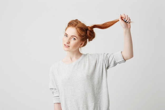 無料写真 若い美しい赤毛の女の子の肖像画は、髪に触れるお団子をほどきます。