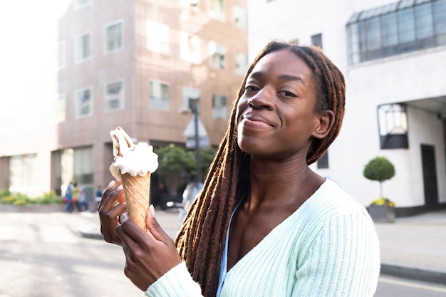 무료 사진 도시에서 아이스크림을 즐기는 아프리카 향취를 가진 젊은 아름다운 여성의 초상화