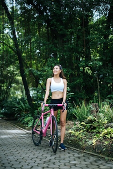 Портрет молодой красивой женщины с розовый велосипед в парке. активативная здоровая женщина.