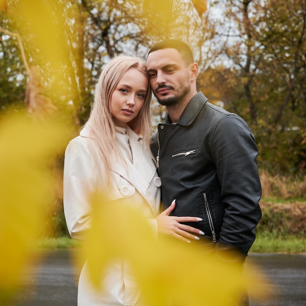 Бесплатное фото Портрет молодой влюбленной пары сквозь желтые листья
