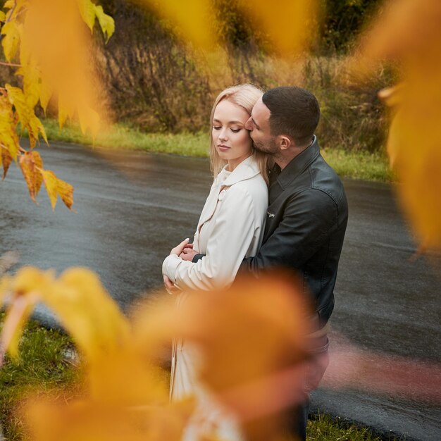 黄色の葉を通して恋をしている若いカップルの肖像画