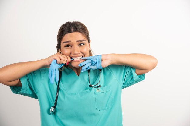 Бесплатное фото Портрет молодой медсестры пытается снять медицинские латексные перчатки.