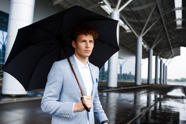 無料写真 雨の通りに黒い傘を保持していると兄弟分の若いビジネスマンの肖像画