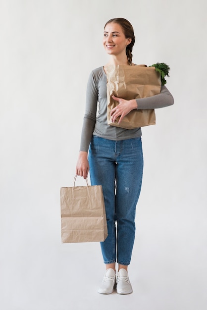 Бесплатное фото Портрет молодой женщины, держащей бумажные пакеты с продуктами