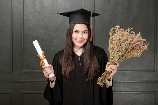 Портрет молодой женщины в выпускном платье, улыбающейся и аплодирующей на черном фоне